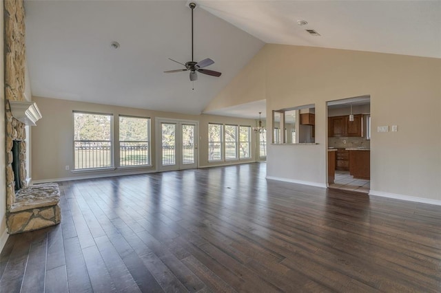 unfurnished living room featuring dark hardwood / wood-style floors, ceiling fan, a stone fireplace, and high vaulted ceiling