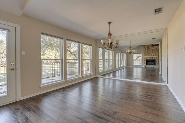 unfurnished living room with an inviting chandelier, a fireplace, and dark hardwood / wood-style floors