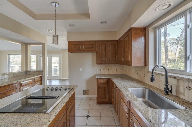 kitchen with light tile patterned flooring, sink, tasteful backsplash, hanging light fixtures, and black electric cooktop