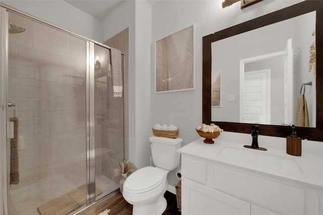 bathroom featuring vanity, toilet, a shower with shower door, and wood-type flooring