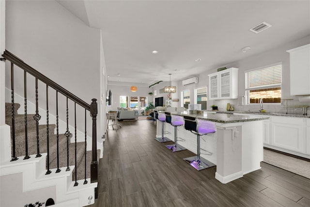 7 Calistoga Cir, Manvel, TX 77578 - kitchen with a wall unit AC, dark wood-style flooring, plenty of natural light, light stone counters, and recessed lighting