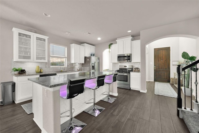 kitchen with stainless steel appliances, white cabinetry, a center island, and a breakfast bar area