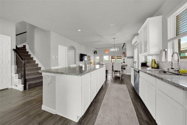 kitchen featuring sink, dishwasher, white cabinetry, a center island, and light stone counters