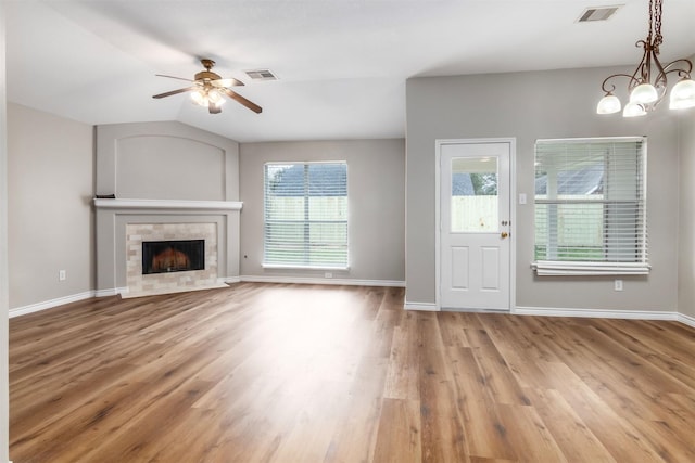 unfurnished living room featuring a tiled fireplace, ceiling fan with notable chandelier, wood-type flooring, and lofted ceiling