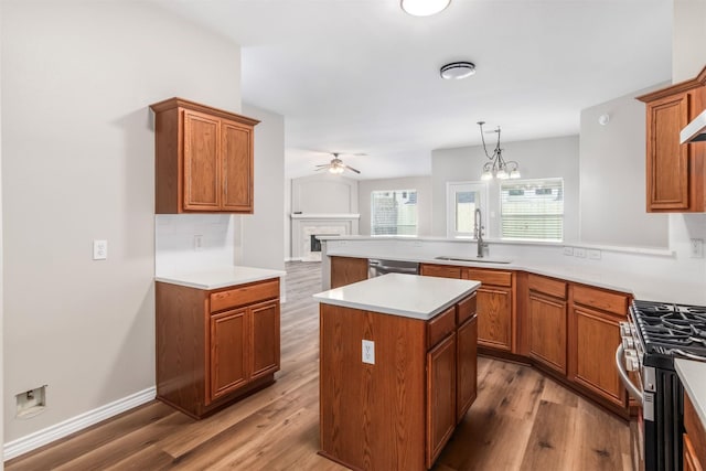 kitchen with sink, wood-type flooring, a center island, hanging light fixtures, and stainless steel appliances