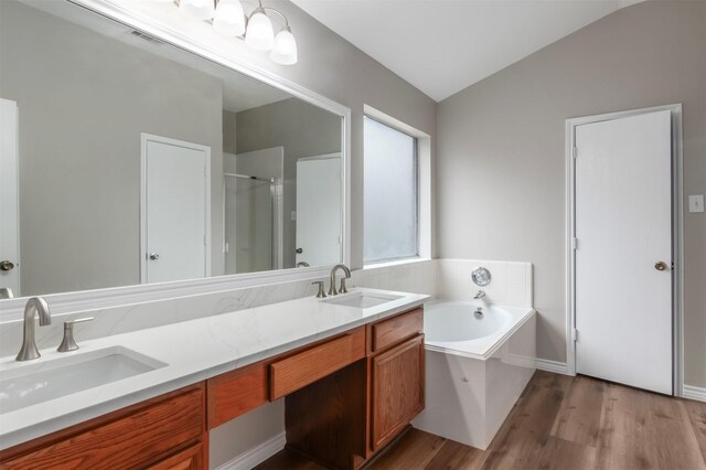 bathroom featuring vanity, vaulted ceiling, plus walk in shower, and wood-type flooring