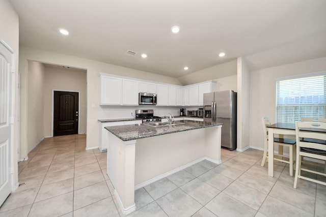 kitchen featuring sink, dark stone countertops, white cabinetry, a kitchen island with sink, and stainless steel appliances