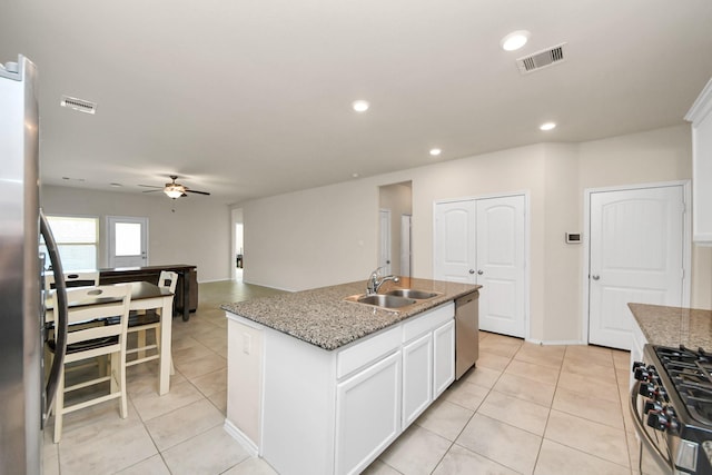 kitchen with sink, white cabinetry, light stone counters, stainless steel appliances, and a kitchen island with sink