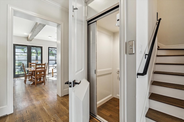 stairway featuring wood-type flooring, elevator, french doors, and beamed ceiling