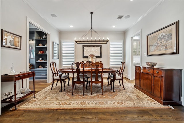 dining space featuring dark hardwood / wood-style flooring, ornamental molding, a chandelier, and a healthy amount of sunlight