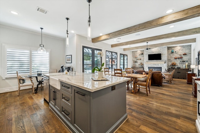 kitchen with dark hardwood / wood-style flooring, a kitchen island, pendant lighting, a fireplace, and light stone countertops