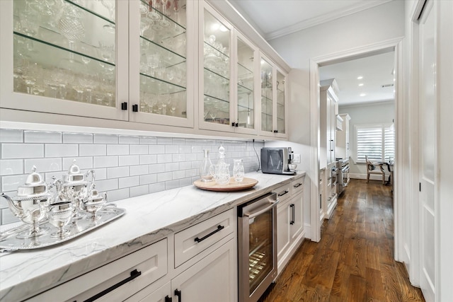 bar with white cabinetry, light stone countertops, ornamental molding, and beverage cooler