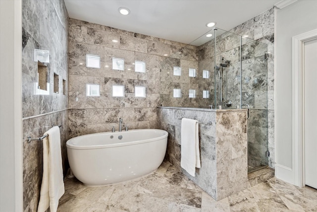 bathroom with shower with separate bathtub and tile walls