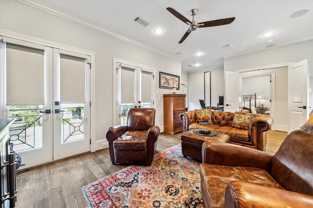 living room with french doors, plenty of natural light, crown molding, and light hardwood / wood-style floors