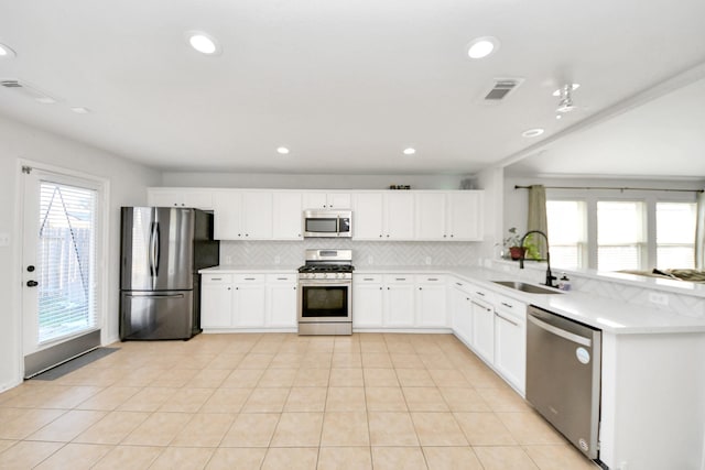 kitchen featuring tasteful backsplash, white cabinetry, sink, light tile patterned floors, and stainless steel appliances