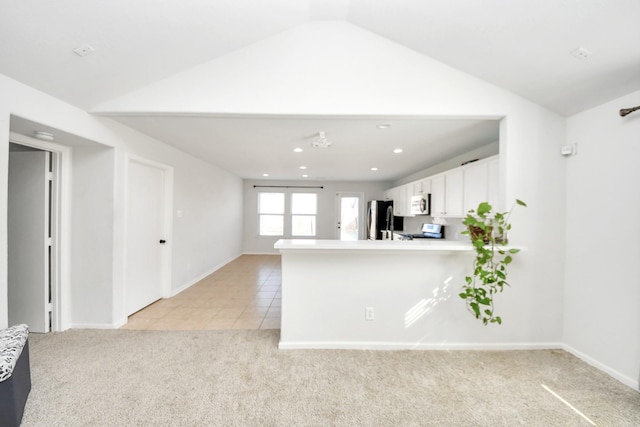 kitchen with lofted ceiling, white cabinets, kitchen peninsula, stainless steel appliances, and light carpet