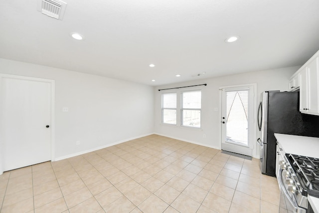 kitchen with stainless steel gas range oven, light tile patterned floors, and white cabinets