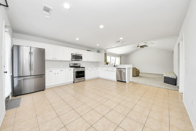 kitchen featuring ceiling fan, white cabinetry, stainless steel appliances, tasteful backsplash, and vaulted ceiling