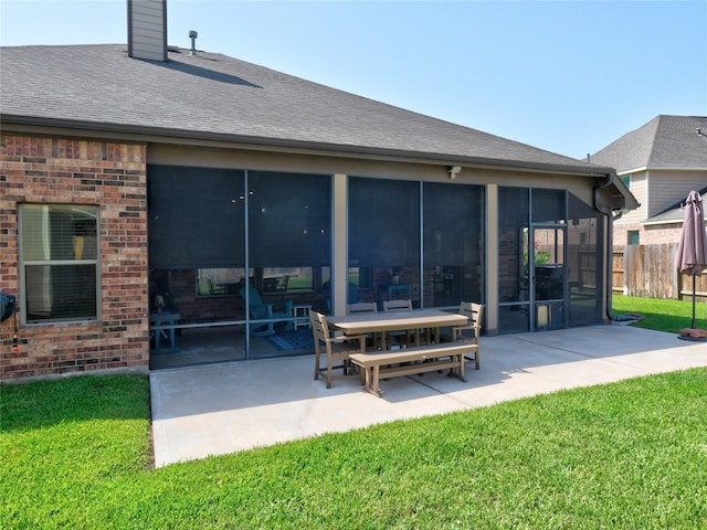 rear view of house with a yard, a patio area, and a sunroom