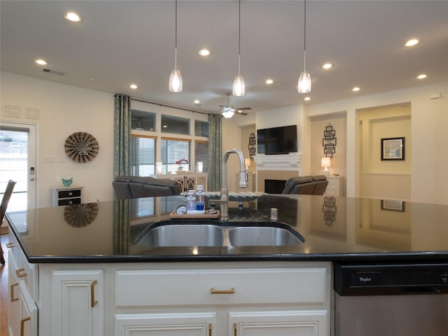 kitchen featuring white cabinetry, stainless steel dishwasher, an island with sink, and sink