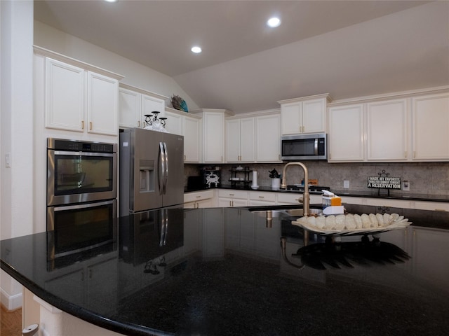 kitchen with backsplash, appliances with stainless steel finishes, vaulted ceiling, and white cabinets