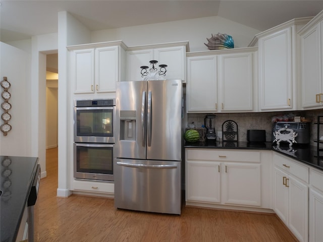 kitchen with lofted ceiling, white cabinetry, light hardwood / wood-style flooring, appliances with stainless steel finishes, and decorative backsplash