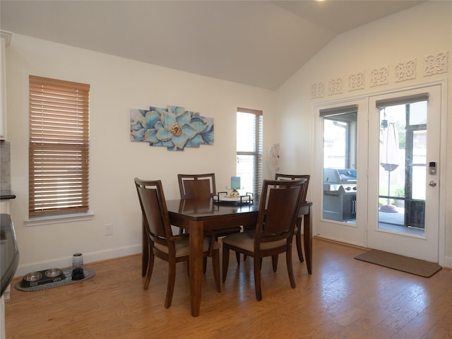 dining room with hardwood / wood-style flooring, vaulted ceiling, and french doors