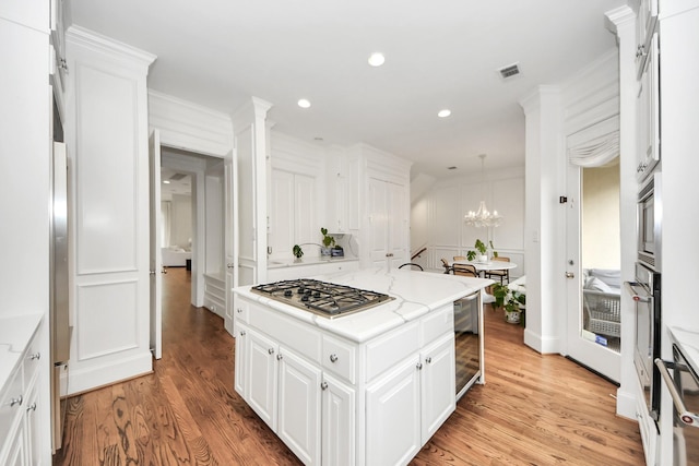 kitchen featuring wine cooler, light stone counters, stainless steel gas stovetop, light hardwood / wood-style floors, and white cabinets