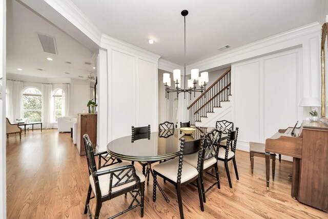 dining space with crown molding, light wood-type flooring, and an inviting chandelier