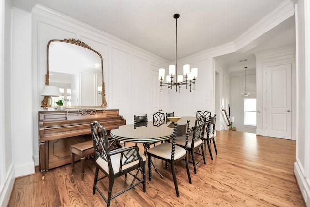 dining room with ornamental molding, a notable chandelier, and light hardwood / wood-style floors