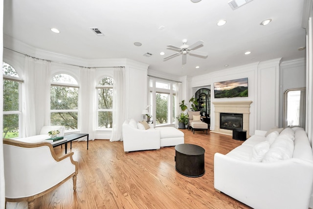 living room with ornamental molding, built in features, and light wood-type flooring