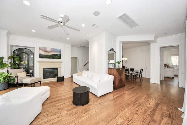 living room with ornamental molding, ceiling fan, and light wood-type flooring