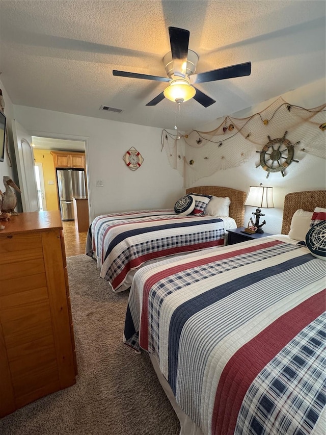 carpeted bedroom featuring ceiling fan, stainless steel fridge, and a textured ceiling