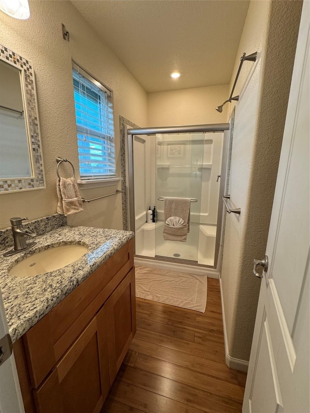 bathroom featuring wood-type flooring, a shower with shower door, and vanity