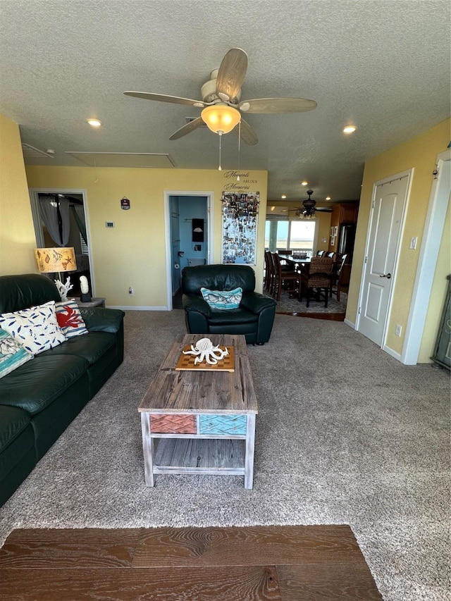 carpeted living room featuring ceiling fan and a textured ceiling