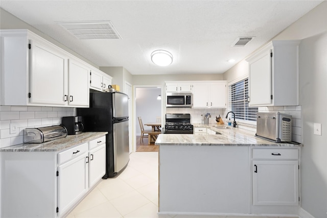 kitchen with stainless steel appliances, white cabinetry, and light stone counters