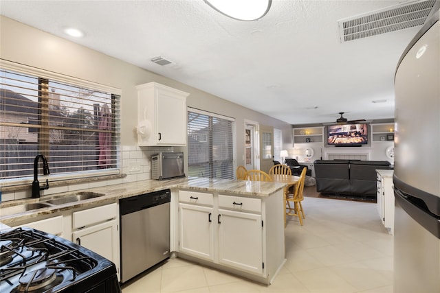 kitchen with sink, appliances with stainless steel finishes, kitchen peninsula, decorative backsplash, and white cabinets