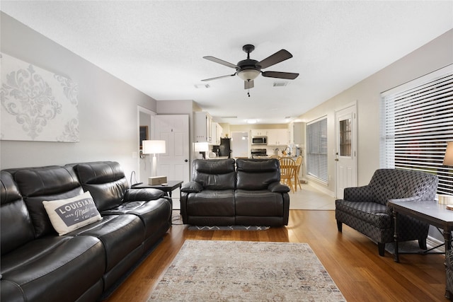 living room featuring hardwood / wood-style flooring, a textured ceiling, and ceiling fan