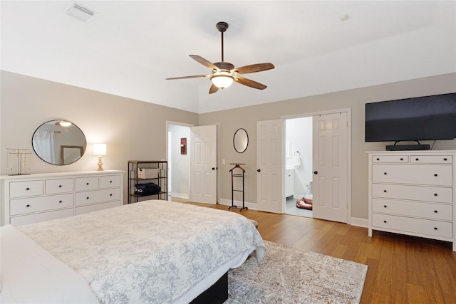 bedroom featuring ceiling fan, lofted ceiling, ensuite bathroom, and light wood-type flooring