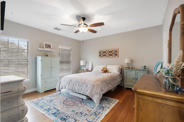 bedroom featuring hardwood / wood-style floors, a textured ceiling, and ceiling fan