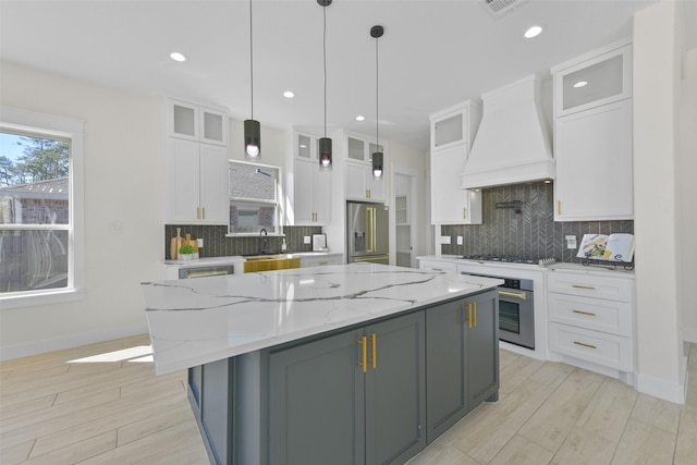 kitchen featuring premium range hood, a kitchen island, light wood-style flooring, stainless steel appliances, and white cabinets