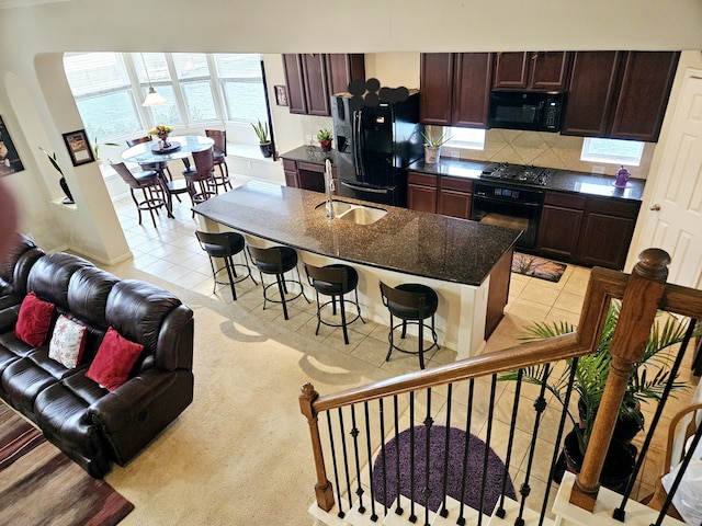 kitchen with light tile patterned floors, sink, backsplash, dark brown cabinetry, and black appliances