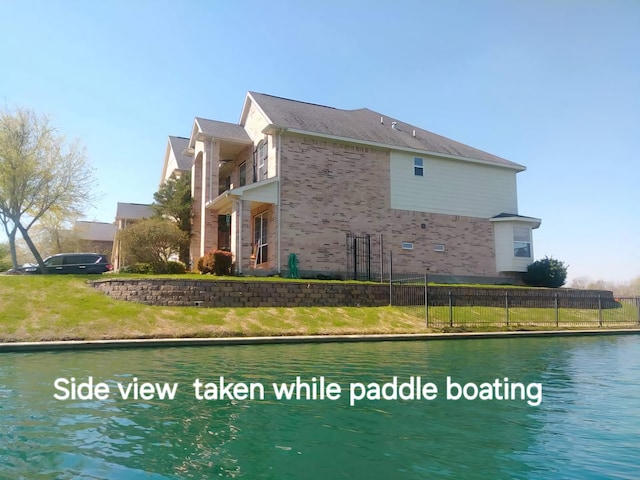 rear view of house with a lawn, a balcony, and a water view