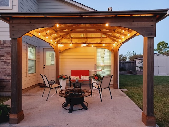 patio terrace at dusk featuring an outdoor fire pit and a shed