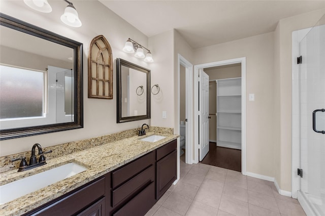 bathroom featuring toilet, vanity, tile patterned floors, and a shower with shower door