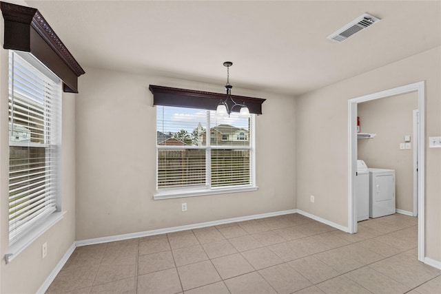 unfurnished dining area featuring a chandelier, light tile patterned floors, and washer and clothes dryer