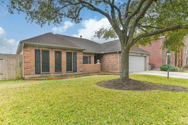 ranch-style home featuring cooling unit, a garage, and a front lawn