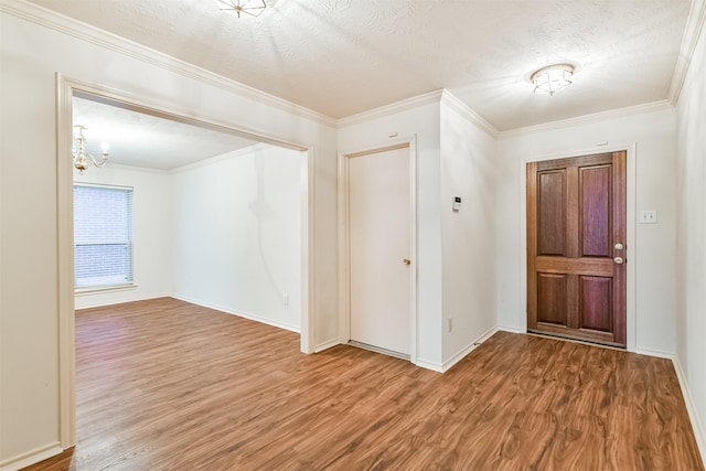 foyer with an inviting chandelier, crown molding, wood-type flooring, and a textured ceiling