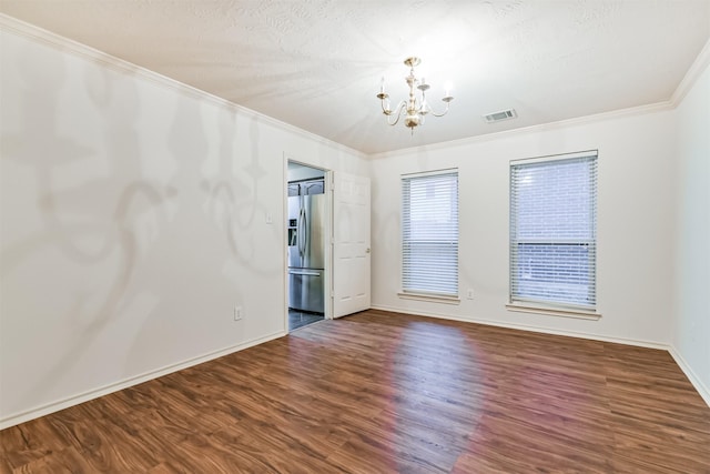 spare room featuring ornamental molding, a textured ceiling, a notable chandelier, and dark hardwood / wood-style flooring