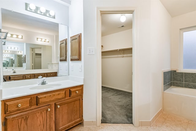 bathroom with tile patterned floors, a bathing tub, and vanity